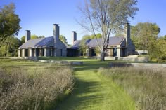 a large house sitting on top of a lush green field next to tall grass and trees