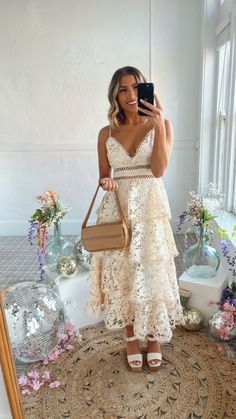 a woman taking a selfie in front of a mirror wearing a dress and holding a purse