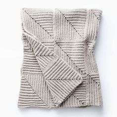 a knitted blanket folded on top of a white surface with an openwork design