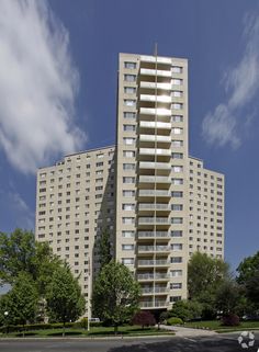 a tall white building sitting next to a lush green park