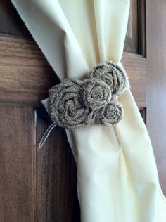 a close up of a tie on a wooden door with white fabric and two flowers