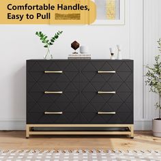 a black dresser with gold handles in front of a white wall and potted plant