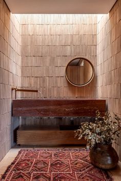 a wooden bench sitting in front of a mirror on top of a wall next to a rug