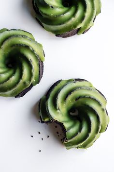 three cupcakes with green frosting and sprinkles on white surface