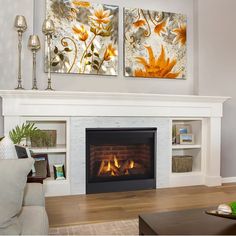 a living room with white furniture and a fire place in the center, two paintings on the wall