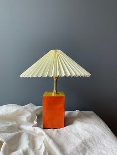 a lamp sitting on top of a white sheet next to a gray wall and floor