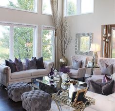 a living room filled with lots of furniture next to large windows on top of a hard wood floor