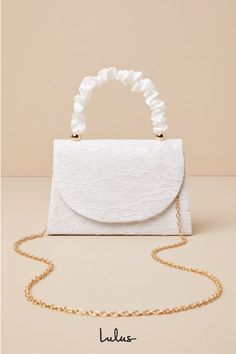 There is no easier way to elevate your springtime looks than with the Lulus Exceptional Class Ivory Lace Ruched Handle Mini Handbag! Chic floral lace (atop woven satin) shapes this cute mini bag that boasts a structured silhouette, a ruched satin top handle with gold beaded accents, and a flat bottom design. The front flap features a hidden magnetic closure that opens to reveal a lined, compact interior with a sidewall pocket. Attach the removable gold chain strap when you want a crossbody look! White Elegant Evening Bag For Summer, Elegant White Evening Bag For Summer, Cream Bags With Pearl Handle For Spring, Spring Cream Bags With Pearl Handle, Chic Spring Fabric Bag, Chic White Summer Evening Bag, Spring Party Bags With Pearl Handle, White Wedding Bags For Spring, Cream Bags For Spring Party