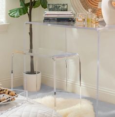 a glass table with two chairs and a potted plant