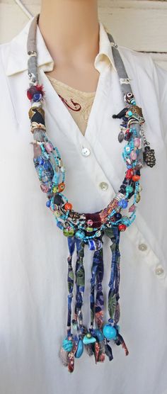 This blue tribal eclectic necklace slips on over the head and is very light, due to the fabric it is made of. It is large, at 37" around, and has 7" of beaded fabric fringe at the bottom.    The beads, that are all over this necklace, are from my collection and are made of: glass, clay, tourmaline, African stained bone, Mexican ceramics, plastic, pot metal, blue stone, and wood. I've also included a leaf charm and a grape cluster charm.    This is a statement necklace that I recently made. It has an elegant feel even though BOHO tribal in nature. I photographed it being worn on a life sized mannequin, and also next to a 12" ruler, to give a sense of size.    Please email if you have any questions about this handmade Art Necklace.    Thanks for looking! Artisan Blue Beaded Necklaces For Festivals, Eclectic Handmade Beaded Necklaces For Festivals, Eclectic Handmade Beaded Necklace For Festivals, Hippie Blue Necklaces For Festivals, Blue Hippie Necklaces For Festivals, Blue Beaded Necklaces For Festivals, Blue Hippie Necklace For Festivals, Artisan Blue Beaded Necklace For Festival, Unique Boho Beaded Necklaces For Festivals