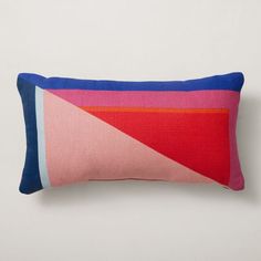 a pink, blue and red pillow on a white wall