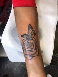 a woman's arm with a butterfly and rose tattoo on the left side of her arm