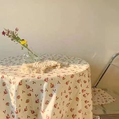 a table with a flower vase on it and a chair in the corner behind it