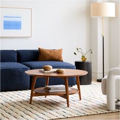 a living room with a blue couch, coffee table and lamp on the side tables