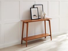 a wooden table with two pictures on it and a vase sitting next to the table