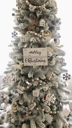 a white christmas tree with ornaments on it and a merry sign hanging from the top