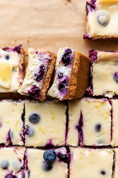 blueberry cheesecake squares are arranged on top of each other with lemon wedges