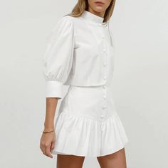 This Women's Summer Cotton Linen White Mandarin Collar 3/4 Sleeve Blouse and High Waist Tight Skirt Set is made from 100% cotton, ensuring softness, comfort, and skin-friendliness. The simple white Mandarin collar blouse pairs perfectly with the high-waisted tight skirt, featuring a playful pleated hem that adds a touch of fashion and charm. This set is ideal for daily wear, commuting, festivals, Valentine's Day, and weddings, offering a perfect blend of elegance and style. Fitted Cotton Tops With 3/4 Sleeves, Stretch Cotton Mini Skirt For Work, Chic Fitted Mini Skirt For Daywear, Fitted Short Cotton Skirt, Fitted Cotton Mini Skirt, Fitted Cotton Skirt For Fall, White Cotton Mini Skirt For Daywear, Fitted Cotton Chic Mini Skirt, Chic Fitted Cotton Mini Skirt