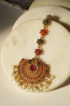 Introducing the Imaari Statement Necklace Set with Maang Tikka and Chandbali Earrings. This exquisite necklace set features multicolor navratan stones with elegant gold plating and high-quality brass filling. The set includes a stunning maang tikka and matching chandbali earrings, making it a perfect style statement for special occasions or parties. The Imaari necklace set is designed to blend tradition with elegance. The intricate design of the maang tikka and the dazzling chandbali earrings co Festive Multicolor 22k Gold Bridal Necklace, Multicolor 22k Gold Temple Necklace For Gift, Gift Multicolor 22k Gold Temple Necklace, Multicolor 22k Gold Temple Necklace Gift, Festive Gold Plated Tikka As A Gift, Multicolor Temple Jewelry Chandbalis With Tilla, Multicolor Chandbalis With Tilla In Temple Jewelry Style, Celebration Temple Jewelry Tikka With Hand Set, 22k Gold Multi-stone Multicolor Jewelry