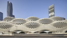 a large building with many wavy designs on it's face and sides, in front of tall buildings