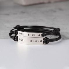 two personalized bracelets with black leather cord and engraving on the front, one for each