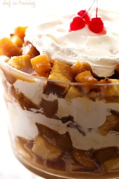 a dessert with fruit and whipped cream in a glass dish on a white tablecloth