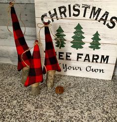 christmas tree farm sign with two red and black buffalo plaid trees on it, next to a pair of wooden burlocks