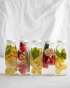 four glass jars filled with different types of fruit