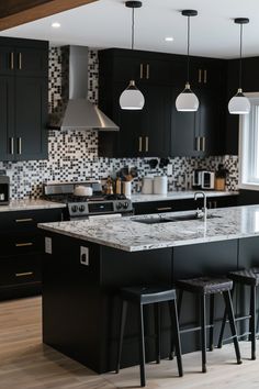 a kitchen with black cabinets and marble counter tops, two stools at the island