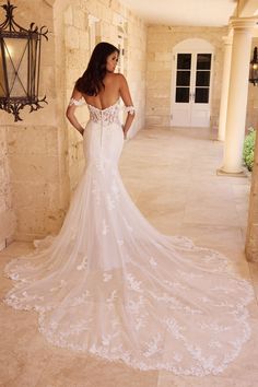 a woman in a white wedding dress standing on a stone walkway with her back to the camera