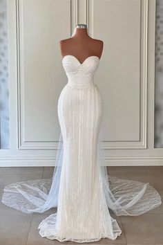 a white wedding dress on a mannequin in front of a wall and floor