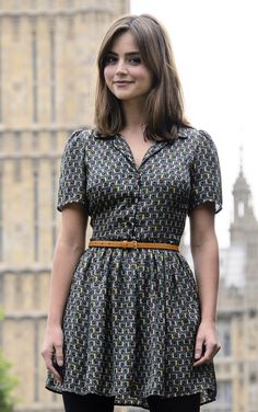 a woman standing in front of the big ben clock tower wearing a dress and tights