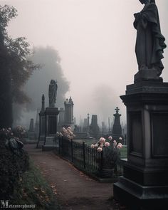 a cemetery with statues and flowers in the foreground on a foggy, overcast day