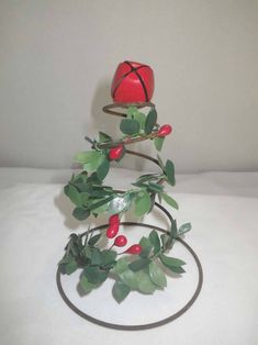 a red apple sitting on top of a metal object with leaves and berries around it