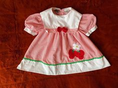 Vintage Dress with Appliquéd Strawberries, Sailor Collar, and Red Bow with Green Rick Rack Trim on Skirt. Brand: Mayfair Kids 65% Polyester, 35% Cotton. Made in Philippines.  Size on Tag: 18 Months. Please take a look at measurements for accuracy. ✂ - - - - - M E A S U R E M E N T S: taken lying flat: Chest/Bust (from Underarm to Underarm): 8 inches (16 inches doubled) Waist Area: 8.5 inches (17 inches doubled) Length (from Shoulder to Bottom Hem): 10.5 inches Vintage Cherry Print Dresses For Spring, Sweet Red Short Sleeve Dress, Casual Red Strawberry Print Dress, Retro Dresses With Strawberry Print For Spring, Retro Spring Dresses With Strawberry Print, Fitted Short Sleeve Dress With Strawberry Print, Cotton Strawberry Print Short Sleeve Dress, Sweet Cotton Dress With Strawberry Print, Pink Cotton Dress With Strawberry Print