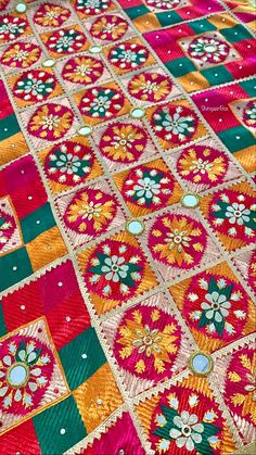 an elaborately decorated table cloth with flowers and circles in red, green, yellow and orange