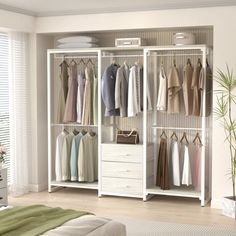 a white closet with clothes hanging on the shelves and drawers in front of a bed