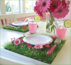 the table is decorated with pink flowers and green grass, along with white plates and silverware