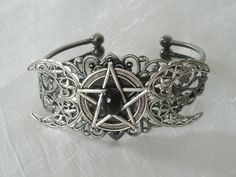 This beautiful silver plated filigree cuff bracelet has a silver plated triple moon design and a pewter silver pentacle with an obsidian setting. Adjustable. Adjustable Silver Gothic Jewelry, Gothic Silver Jewelry For Festival, Adjustable Gothic Silver Jewelry, Gothic Silver Festival Jewelry, Gothic Adjustable Bracelet, Adjustable Gothic Bracelet, Adjustable Mystical Silver Bracelet, Adjustable Silver Mystical Bracelet, Silver Spiritual Metal Cuff Bracelet