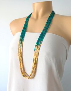 a woman wearing a white top and green beaded necklace on a mannequin