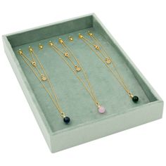 four necklaces in a green box on a white background