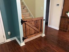 an open door in the middle of a room with wooden floors and stairs leading up to a second floor