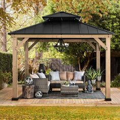 a wooden gazebo sitting on top of a patio next to a lush green field