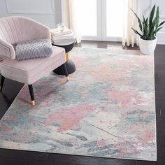 a pink chair sitting on top of a wooden floor next to a white and gray rug