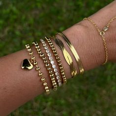 a woman's arm with several bracelets on it and a heart shaped diamond