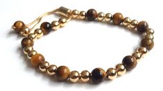 "Tigers Eye Bracelet This modern and stunning Shamballa bracelet is made with an adjustable chain brass 18k gold plated and beaded with an 8mm genuine tiger eye beads, and gold-filled balls. It is a nice piece for everyday use and combines with any casual outfit. This is a perfect Birthday, graduation, Christmas or Mothers day gift. The bracelet is adjustable to any wrist size with a comfortable sliding clasp closure. It can be adjusted from 6\" to 9\" inches approximately. Each item is carefull Adjustable Yellow Gold-plated Crystal Bracelet, Gold Adjustable Bracelet With Sliding Knot, Adjustable Gold-tone Luxury Bracelets, Adjustable Gold Bracelet With Sliding Knot, Adjustable Yellow Gold Rosary Bracelet, Gold Adjustable Resizable Bracelet, Adjustable Gold-plated Crystal Bracelet As Gift, Adjustable Gold Rosary Bracelet, Adjustable Gold Jewelry With 8mm Beads