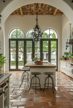 a kitchen with an arched ceiling and tile flooring that has two stools at the center