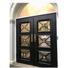 two black double doors with gold handles and glass panels on the front of a building