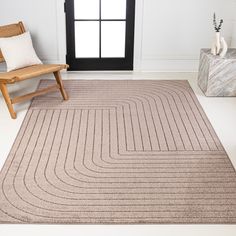 a beige rug with wavy lines on it in front of a chair and windowsill