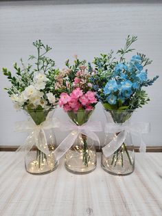 three vases filled with flowers on top of a table